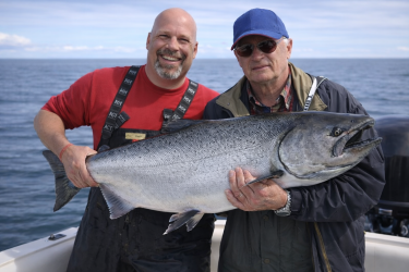 Captain Randy Zinck and a guest with a salmon aboard a Live Life Coastal charter